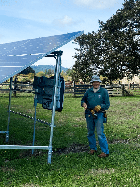 Thom Pence standing next to new solar panel install at Red Mill Farm on San Juan Island San Juan Preservation Trust